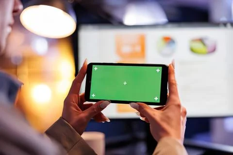 Person using smartphone with green screen interface in modern room Stock Photos