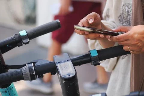Person Using Smartphone to scan the QR code of the Electric Scooter Handlebar 库存照片