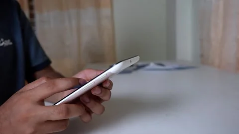 Person using smartphone at a table indoors Stock Footage 318578340