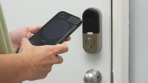 Person using smartphone to unlock smart door lock with visible screen interface Stock Footage 332578491