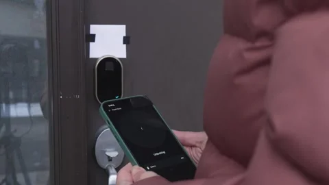 Person using smartphone to unlock smart door lock, showing progression from Stock Footage 332578501