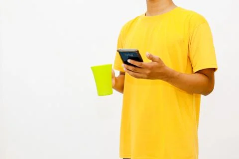 Person using smartphone while holding vibrant green drink cup on white back.. Foto stock