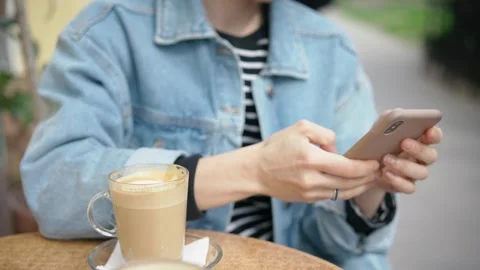A person using a smartphone while sitting on the outdoor terrace of a cafe Stock Footage 267539166