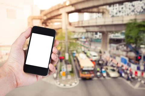 Person using smartphone white screen holder on hand with  blurry of traffic j Stock Photos