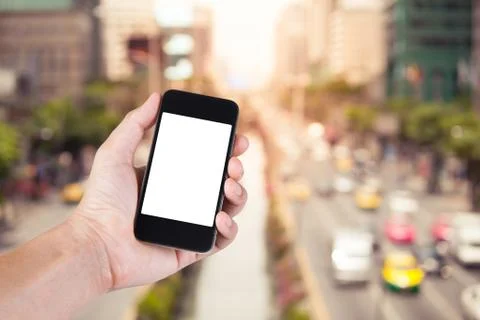Person using smartphone white screen holder on hand with  blurry of traffic j Stock Photos