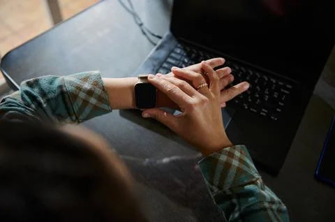 Person Using Smartwatch While Working on Laptop in a Home Office Setting Foto stock
