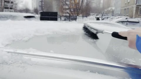 A person is using a snow brush to clear snow off a car Stock Footage 269868363