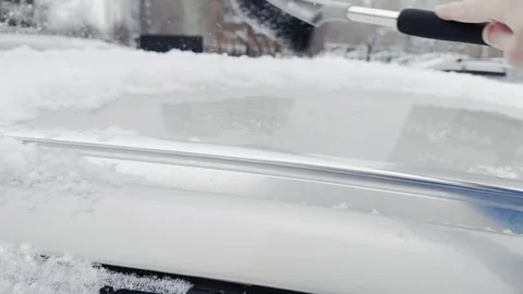 A person is using a snow brush to clear snow off a car Stock Footage 279057142