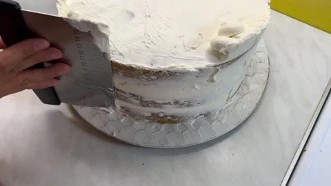 Person using spatula to frost cake on table with baked goods Stock-Footage 283376705