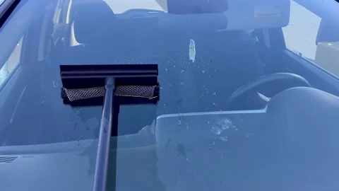 Person using a squeegee to clean soap and water off car windshield Stock Footage 348694518