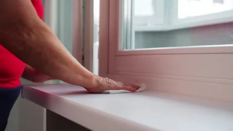 A person is using a squeegee to clean a window, removing water droplets from the Stock Footage 333646976