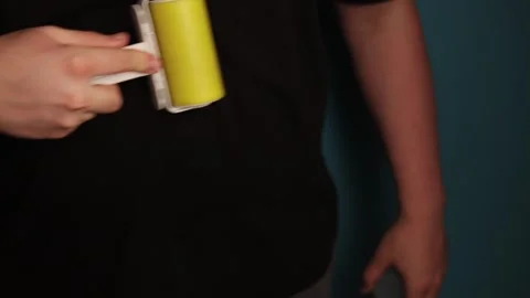 Person using a sticky lint roller to clean black clothing surface Stock Footage 340265743
