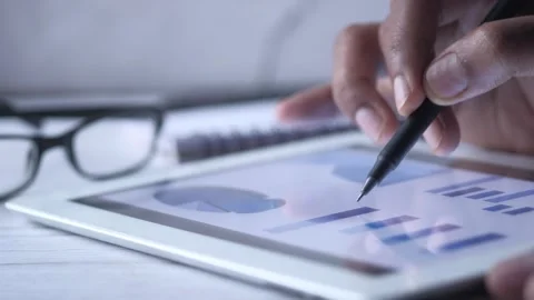Person using stylus on tablet analyzing financial charts, close-up motion. Stock Footage 332858383