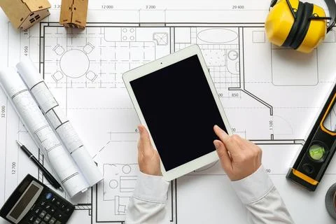 Person using tablet on architectural blueprint with construction tools Stock Photos