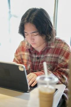 Person using tablet beside cold drink Stock Photos