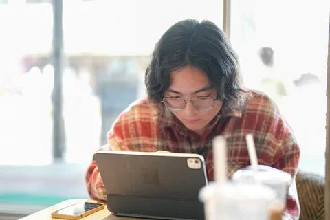 Person using tablet beside iced drink Stock Photos