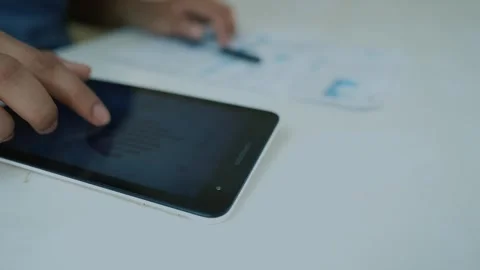 Person using a tablet with charts, blurred background Stock Footage 320725261
