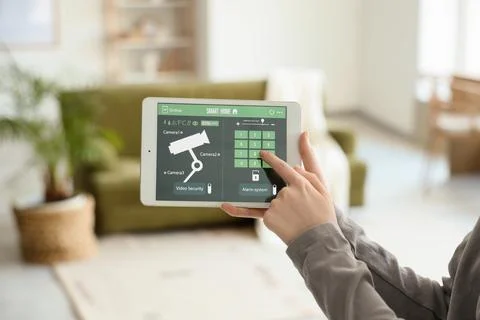 Person using a tablet to control smart home security and alarm system in a mo Stock Photos