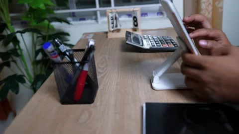Person using a tablet at a desk with a calculator and pens Stock Footage 317736890