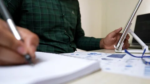 Person using a tablet at a desk with documents and charts Stock Footage 318056608