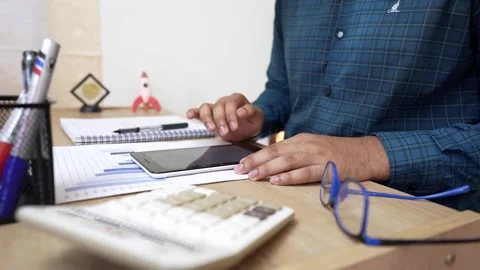 Person using a tablet at a desk with office supplies Stock Footage 320725383