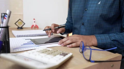 Person using a tablet at a desk with office supplies Stock Footage 320725401