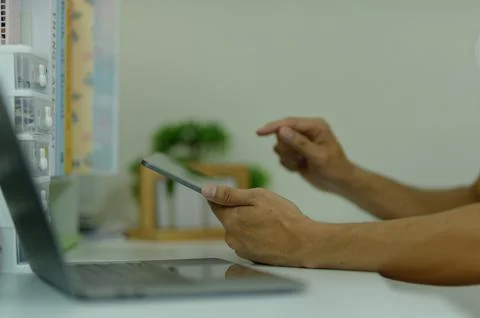 Person Using Tablet Device in Modern Office with Laptop and Shelves Stock Photos