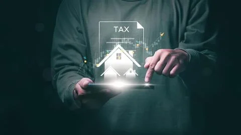 Person using tablet with house and tax icons in dark room Stock Photos