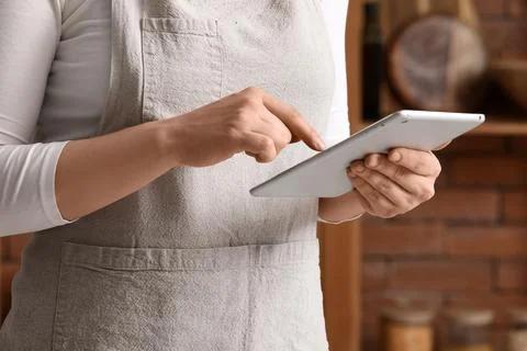 Person using tablet in kitchen wearing apron Stock Photos