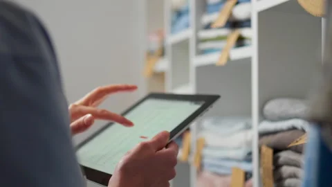 Person using a tablet to manage inventory in a well-organized storage room Stock Footage 323714094