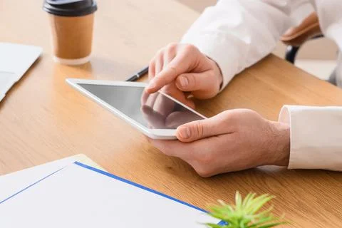 Person using tablet at office desk with coffee cup Stock Photos