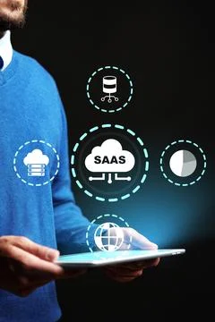 Person using tablet with SaaS icons in dark background showing software service Stock Photos