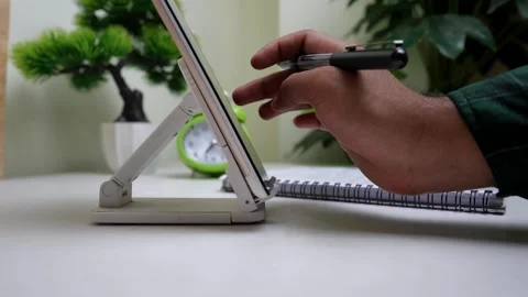 Person using a tablet with a stylus on a desk Stock Footage 320724955