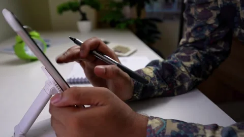 Person using a tablet with a stylus in a home office setting Stock Footage 316800008