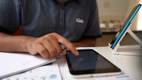 Person using a tablet with a stylus, taking notes on paper video shot Stock Footage 318056715