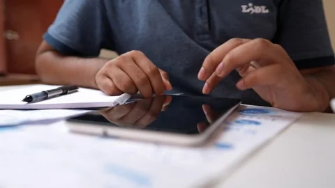 Person using a tablet with a stylus, taking notes on paper video shot Stock Footage 318056721
