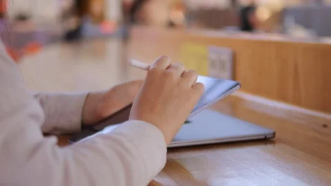 Person is using a tablet on a wooden table Stock Footage 316975954