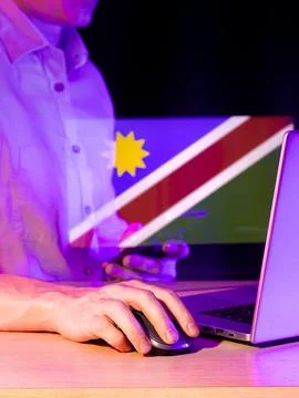 Person using tech with blue-red-green flag and yellow sun overlay in neon p.. Foto stock