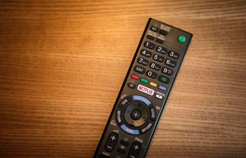A person using a television remote with a dedicated Netflix logo on the butto Stock Photos