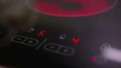 Person using the timer function of an induction cooktop. Slow camera pan. Video stock 166601834