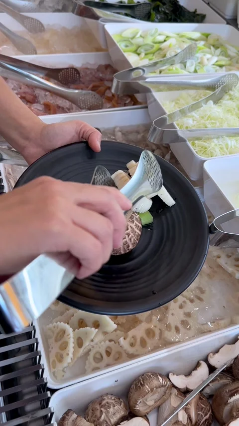 Person Using Tongs to Select Fresh Vegetables at a Buffet Stock Footage 334165293