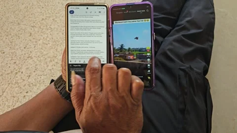 Person Using Two Smartphones Multitasking Typing Notes And Watching Video Stock Footage 340029438