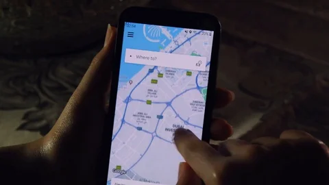 A person using the Uber app on a phone - Abu Dhabi and Dubai city Stock Footage 113648211