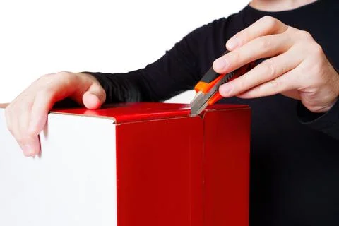 Person Using a Utility Knife to Open a Red and White Box Stockfoto's
