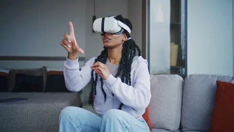 Person using virtual reality headset while sitting on a sofa in a living room du Stock Footage 339370017
