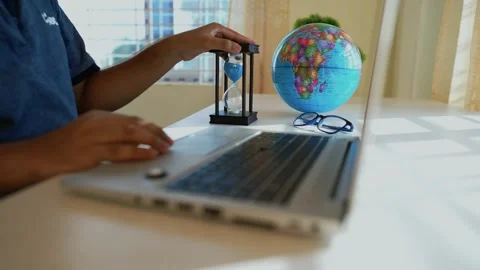 Person using a VR headset at a desk with a laptop and globe Stock Footage 316745073