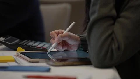 A person using white digital pen to write on a tablet screen on the work desk Stock Photos
