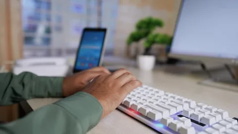 Person using a white mechanical keyboard at a desk with a tablet and monitor Stock Footage 320724113
