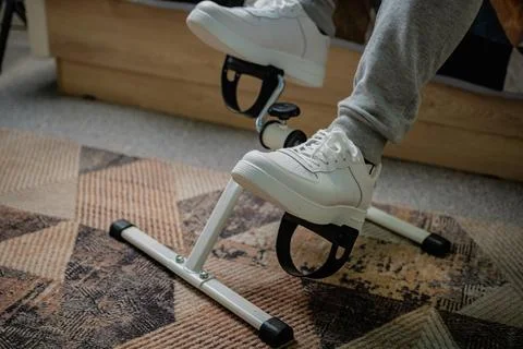 Person Using White Peddler Exercise Machine While Sitting Stock Photos