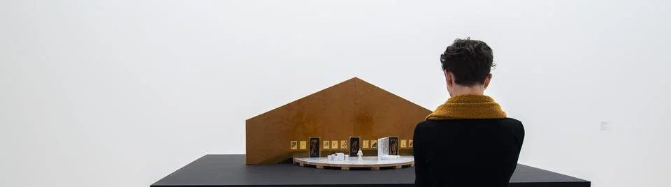 Person views artwork of a tiny model home in a museum Stock Photos